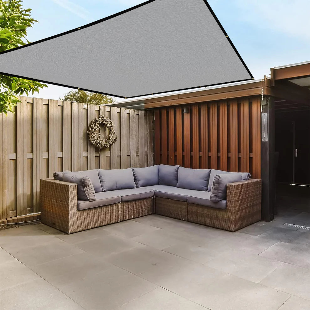 Outdoor patio with wicker sectional sofa, wooden fence, and awning.