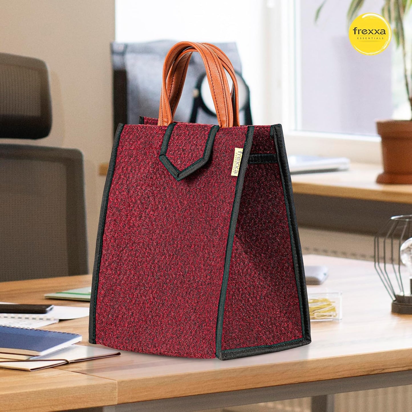 Red textured tote bag with orange handles on a desk, featuring the frexxa brand.