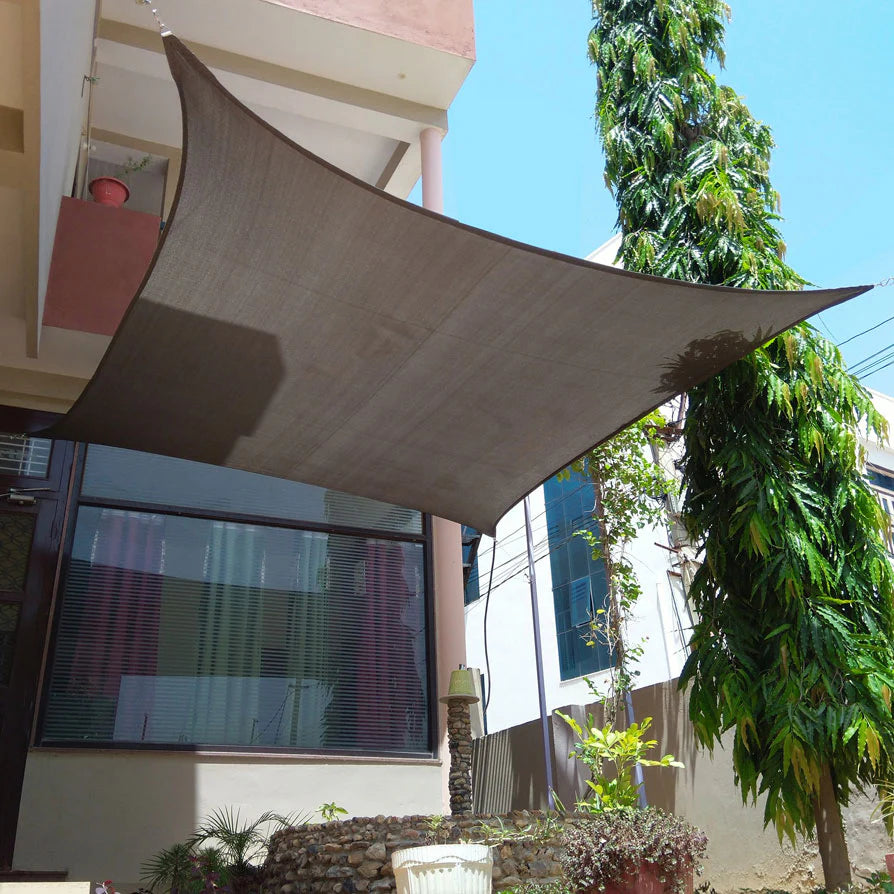 Brown shade sail over a building with trees and a clear sky