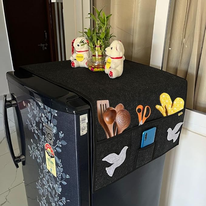 Small refrigerator with a black storage unit on top holding kitchen utensils and decor items.
