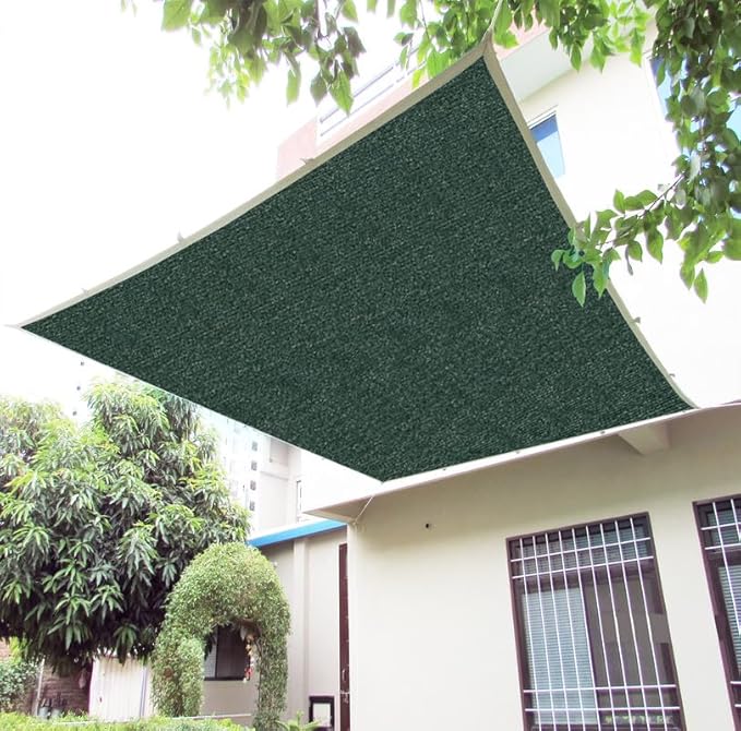 Green sunshade sail attached to a building with trees in the background