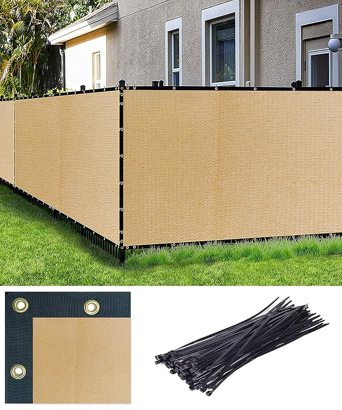 Beige privacy screen fence with black ties on a grassy area in front of a house.