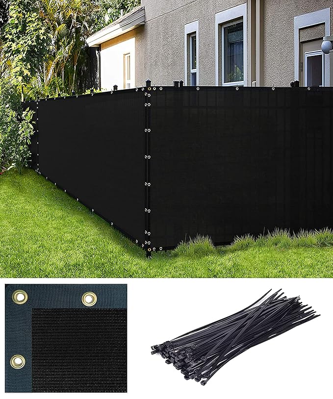 Black privacy fence screen with grommets and ties on a grassy area with a house in the background.