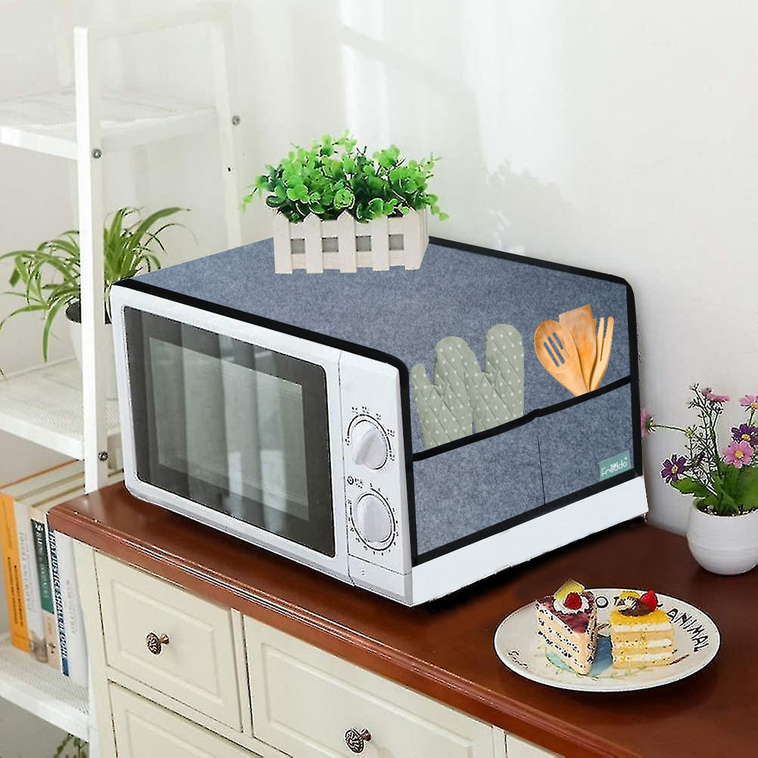 Microwave with a cover on a wooden surface with decorative items