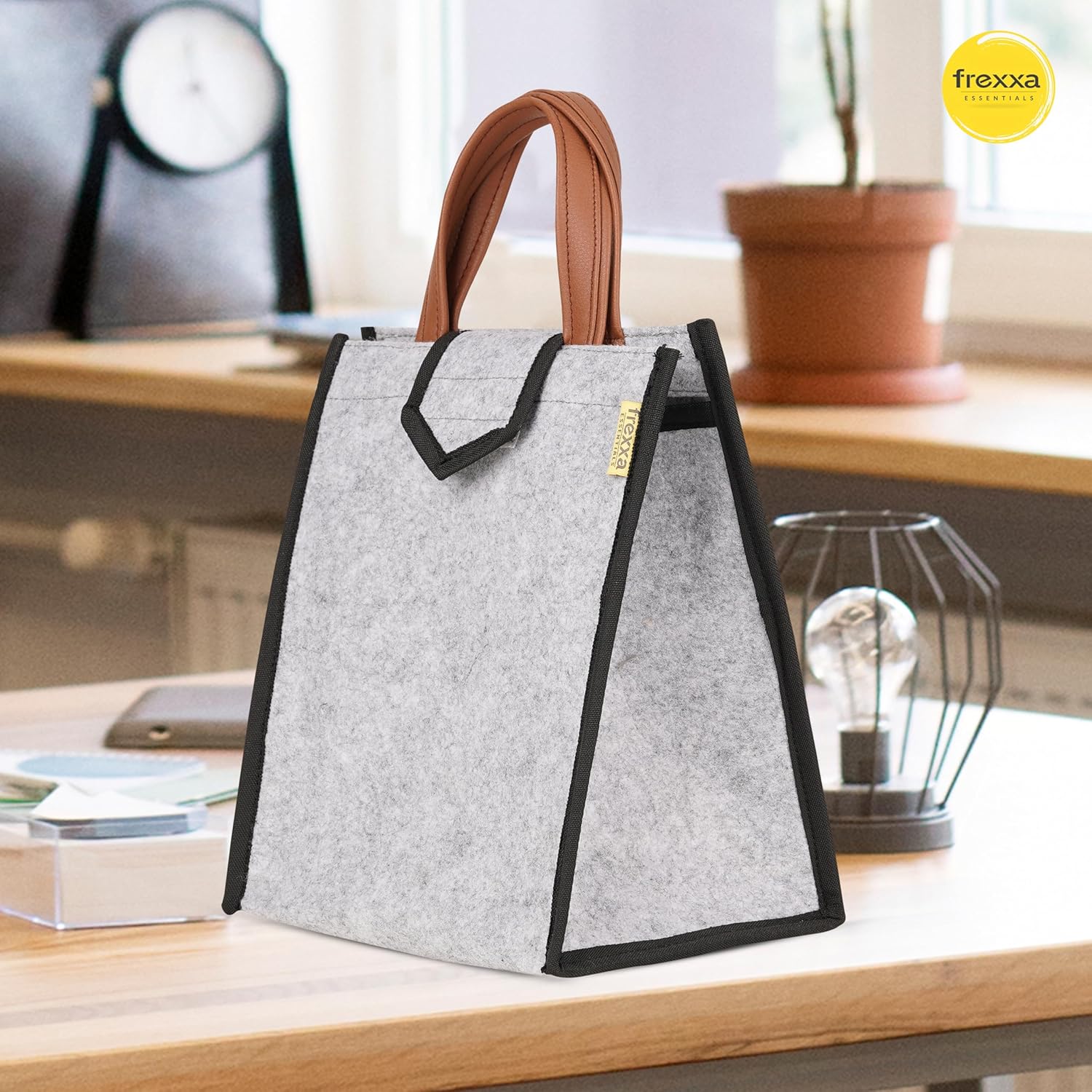 Gray tote bag with brown handle on a desk, featuring the frexxa brand.