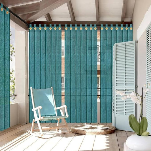 Teal outdoor curtains with decorative rings in a patio setting with a rocking chair and plant.