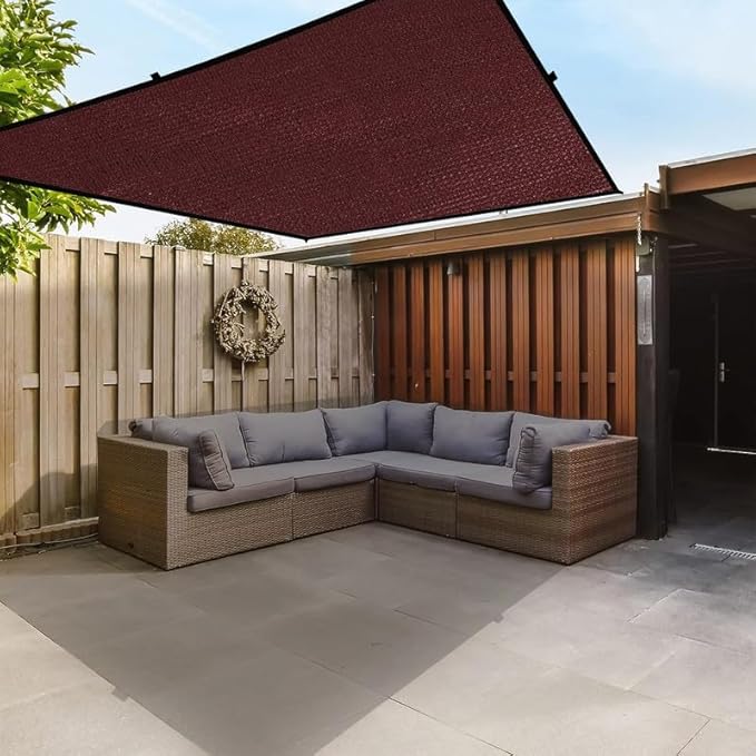 Outdoor patio with a sectional sofa, canopy, and wooden fence.