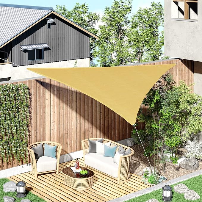 Yellow triangle-shaped sunshade over a patio area with furniture and plants.