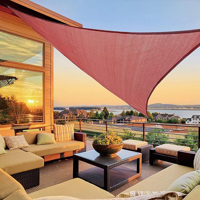 Outdoor patio with a red shade sail, couches, and a coffee table with a scenic view.