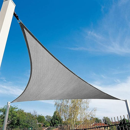 Gray triangle-shaped sunshade against a blue sky with trees in the background
