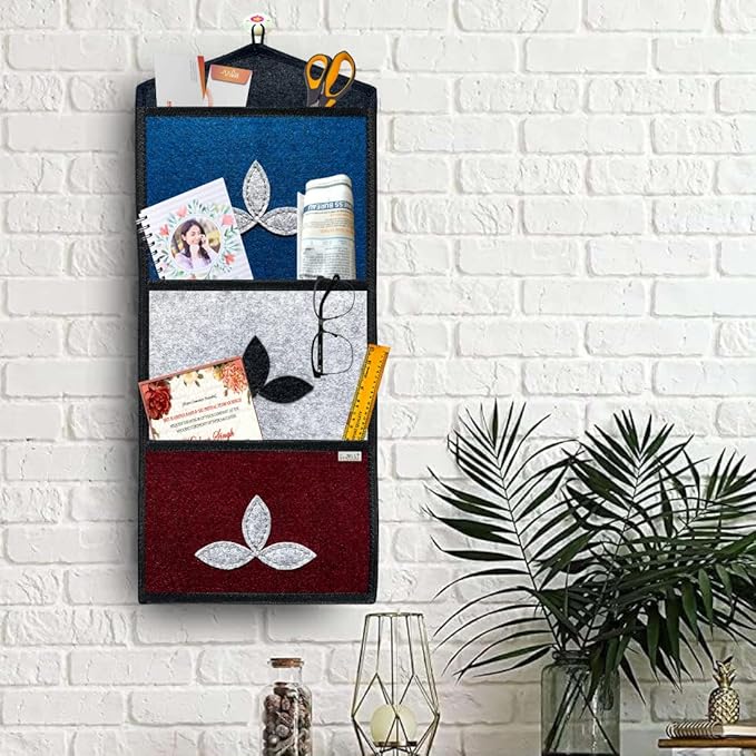 Wall-mounted organizer with compartments holding stationery items against a white brick wall.